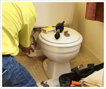 handyman repairing plumbing issues in bathroom